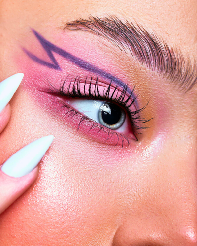 closeup shot of a woman with pink eyeshadow and purple graphic eyeliner