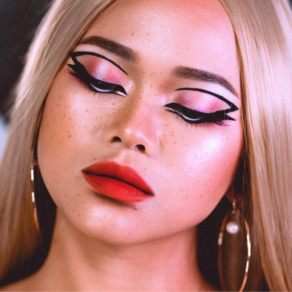 image of a blonde woman with bold graphic eyeliner, red lipstick, and glowing skin